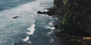 Green coastal cliffs meeting blue ocean waves