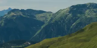Green alpine valley and mountain peaks under a blue sky